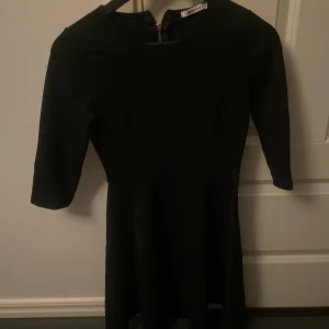 Svart klänning  - Enkel svart klänning, något insydd vid höften. Lite tjockare material än vad klänningar brukar ha.