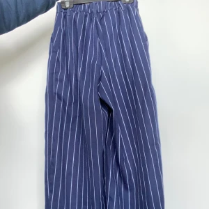 Randiga tygbyxor - Mörkblå tygbyxor med vita ränder i storlek 32. Högmidjade. Köpta på H&M. Uppsydda då dom var för långa (se sista bilden)  Hör av dig vid intresse!💗