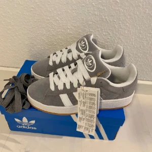 Nya Adidas Originals Campus 00s stl: 36 2/3 - Adidas Originals Campus 00 s j Storlek: 36 2/3 Färg: Grå (Grey Three / Cloud White / Cloud White) Ingår både vita och gråa skosnören.  Nya och oanvända. Ligger kvar i kartong. Köpta i Sverige och inte från en massbeställning utomlands. 