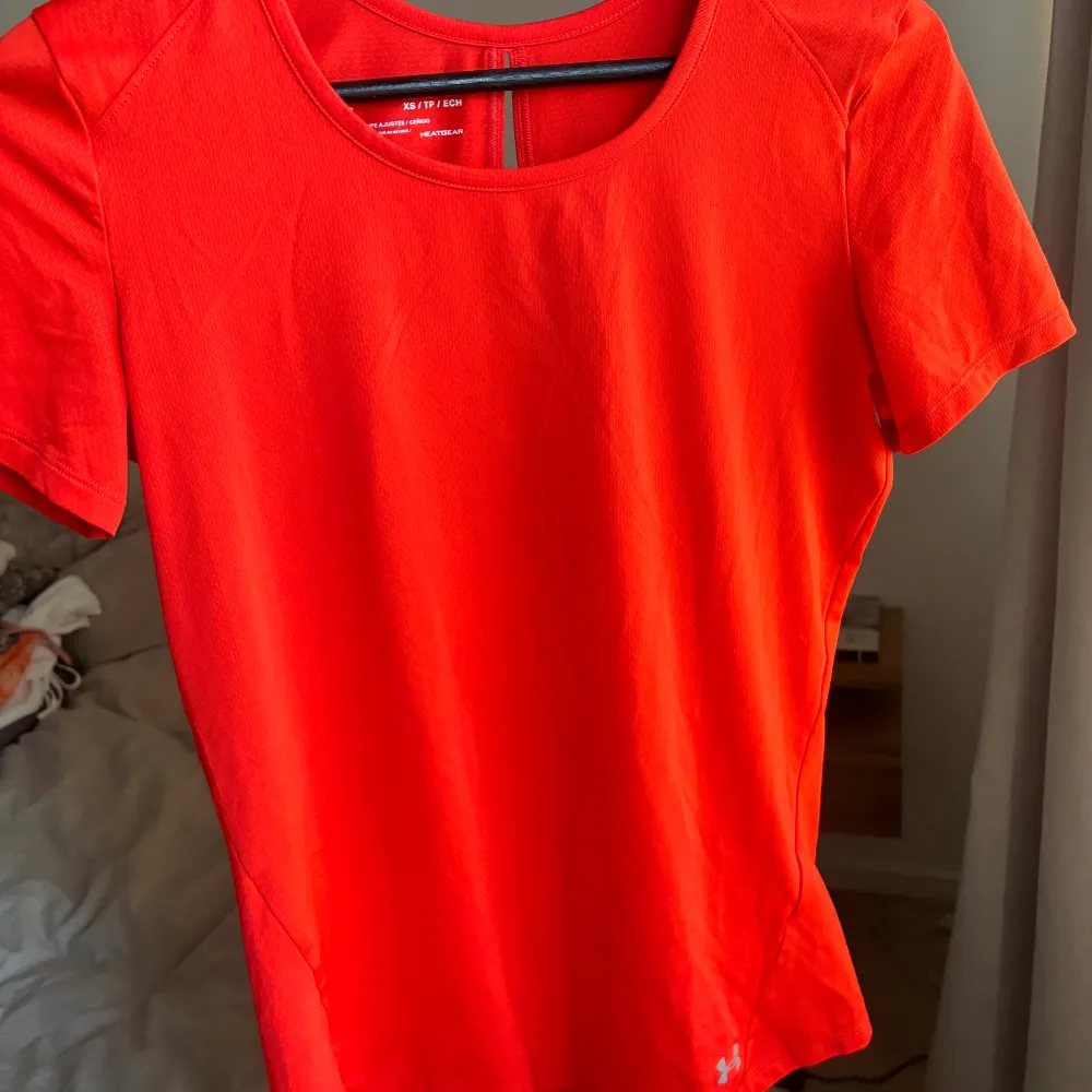 Nyskick. Funktions t-shirt från under armour i aprikos/orange-röd fin färg.. Sport & träning.
