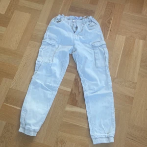 Cargo pants - Ett par vita/beiga cargo pants, byxorna har en blå liten fläck på låret som inte går bort. Men annars så är dem i bra skick! Dem är i storlek 160.