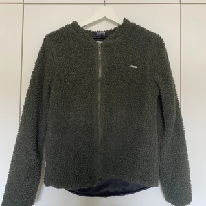 Mörkgrön tröja  - Mörkgrön tröja med dragkedja från Aim’n i storlek S. Mysig att ha på sig före & efter träning. Glansigt material inne i som gör att den känns väldigt lätt på 