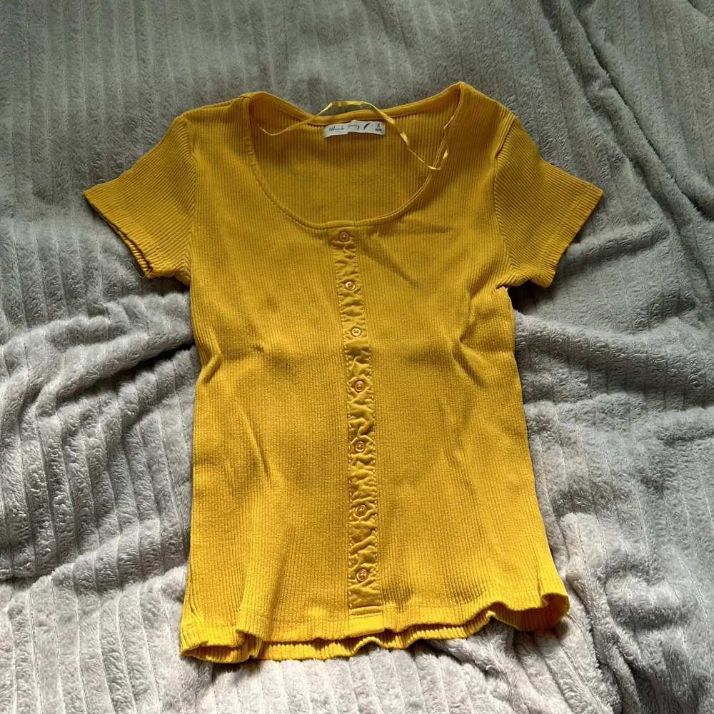 Gul t-shirt i storlek S men vet inte vad märket heter men ni ser namnet på bilden! Den är lite gul orange men väldigt fin till sommaren och är aldrig använd. T-shirts.