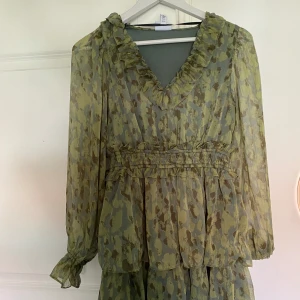 Volangklänning grön  - Säljer min oanvända klänning som jag köpte förra sommaren. Jag har storlek XS och är 165 cm lång och upplever den inte kort. 