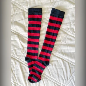 Rödsvarta knästrumpor - Rödsvarta knästrumpor Köpta på plick men endastsnvönt en-två tillfällen. Tvättade och fortfarande väldigt fina. Onesize.