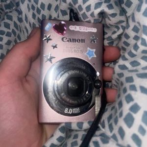 Canon Ixus 80 is - Kameran funkar men har ett objektivfel. (Dvs problem med linsen) Som gör att det inte går att ta bilder med den! Det går att laga det men jag orkar inte och har inte nån skruvmejsel. Den här kameran är förövrigt otroligt sällsynt. Laddare ingår.