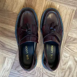Storlek 38. Helt oanvända loafers i skinn av märket UK Look. Oxblodsfärgade. Nyskick.