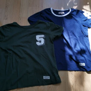 2st T-shirts - 2st T-shirts i mörkblå och mörkgrön med nr 5 som tryck. Storlek XS, använt skick, den gröna har fläck fram (se bild), annars fina. Hämtning, annars betalas frakt av köparen. Bara att skriva vid frågor eller bud! 🌻 