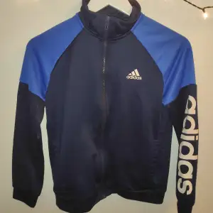 Snygg Adidas jacka i storlek M. Den är i färgerna blå och svart. Perfekt gympa jacka. Inga hål eller liknande