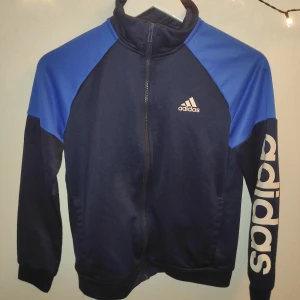 Adidas jacka  - Snygg Adidas jacka i storlek M. Den är i färgerna blå och svart. Perfekt gympa jacka. Inga hål eller liknande