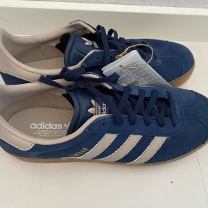 Nya retro Adidas Gazelle - storlek 37 1/3 - Adidas originals gazelle j i storlek 37 1/3. Färgen är marinblå och beige (night indigo/wonder taupe) Nya och oanvända med tags.  Populär färg med vintage inspiration.  Slutsålda.  Handball Spezial Samba