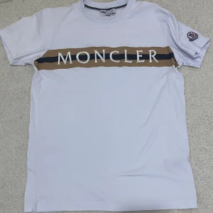 Moncler t-shirt - Vit Moncler t-shirt Skick 8/10 Helt ren och knappt använd T-shirt perfekt för sommar Kan fixa fler bilder!!! 