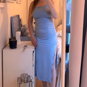 Blå midiklänning  - Blå midiklänning med tunna straps, inte justerbara. En liten knyt detalj i ryggen och en slits vid sidan av benet. Plus en likadan i rosa så två klänningar 