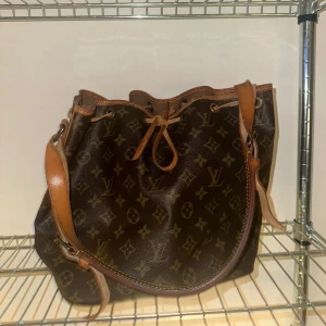 Louis Vuitton petit noe - Intressekoll för min Louis Vuitton petit noe, köpt second hand och är äkta. Inga defekter eller skador. Den är lite sliten vid vissa kanter men inte sönder på något sätt. ✨ Höjd 25 cm, bredd 24 cm, djup 18 cm. 