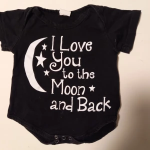 Svart body strl. 56 - Svart body med texten "Love you to the moon and back". Ungefär storlek 56, se bild 3 för jämförelse med en annan body från Lindex i storlek 56. I fint skick, inga hål eller fläckar. Unisex  Tvättad i parfymfritt tvättmedel och utan sköljmedel.