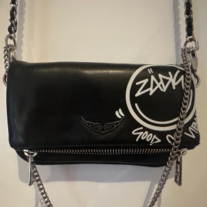 Zadig väska - Säljer denna super coola Zadig & Voltaire väska 💕💕 Köpt för ca 2,5 år sedan, en av dragkedjorna är lite miss färgad men det är inget som syns/som man märker av (skriv för bild 🥰) Köpt för ca 2300 (priset kan diskuteras såklart!)