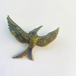 Brosch  - Guldfärgad brosch mockaingjay Gott skick 