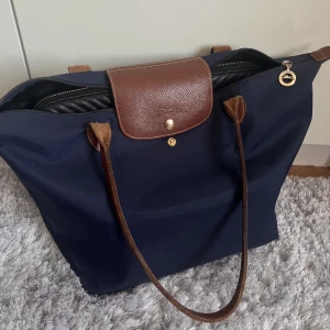 Longchamp Väska le pliage original tote navy - Säljer min Longchamp väska från 2017. Den är i bra skick för att vara 7 år gammal. Lite slitningar på underdelen på kanterna men annars är den som ny. På grund av slitaget säljer jag den för 550kr. Skriv gärna privat för frågor eller fler bilder🥰🥰