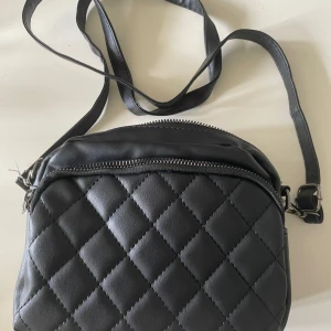 En svart axelremsväska  - Flera fickor, bra skick.