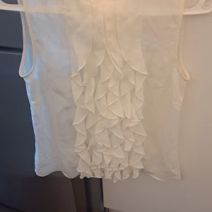 Jättefin blus  - Med volanger fram och öppning i rygg med knapp. Som ny.