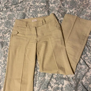 Beiga kostymbyxor  - Beiga kostymbyxor med en liten fläck på baksidan som syns på bild två och tre. Jättebra skick i övrigt! Är lite ljusare än de är på bilden och är mer på det vita hållet.  Midjemått 75cm och innerbenslängd 76cm