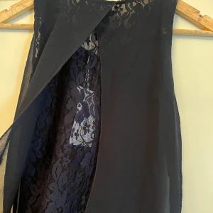 Linne med spets  - Marinblått linne i blusmaterial med öppning i ryggen där man ser spetsen. Storlek M men passar mindre också. Aldrig använd, prislapp finns kvar.   Pris är diskuterbart. Hör gärna av er för fler bilder eller frågor, lite svårt med alla bra bilder här