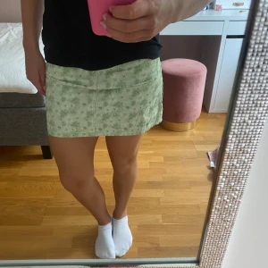 Grönblommig kjol - Här är en grön kjol med blommigt mönster. Kjolen är köpt för 2 år sedan på Na-Kd. Det är misslisibells kollektion som hon släppte. Säljer pga för liten i storlek. Det är storlek S. Fint skick. Pris kan diskuteras