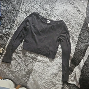 Svart långärmad topp från H&M - En svart långärmad topp från H&M med en enkel design. Toppen är tillverkad av ett mjukt material och har en normal passform.