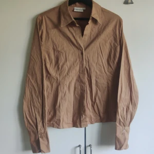 Skjorta - Brun/beige skjorta från cappuccini. Bra skick förutom att den saknar en knapp (näst översta, se första bilden). Storlek L.