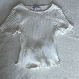 T-shirt med knyte i ryggen  - Säljer en jättegullig vit ribbad t-shirt med knyte i ryggen från new yorker. Etiketten sitter fortfarande kvar då den förut har blivit använd, bara prövad. Den är ganska stretchig så kan passa XXS-S. Om du vill ha fler bilder är det bara att skicka💕