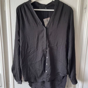 Svart blus  - Fin svart blus som aldrig har blivit använd. Prislappen sitter kvar. Aldrig blivit använd då den inte riktigt är i min stil. I mycket bra skick. 