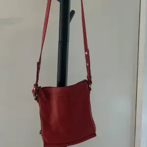 Fin röd skinnväska från Ecco. Bra skick. Lite mindre väska perfekt för det nödvändiga. Har ett långt band som går att justera. 