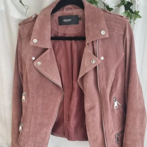 Smutsrosa jacka  - Smutsrosa jacka. Två fickor på vardera sida samt dragkedja med knappar på sidorna för att stänga jackan. 