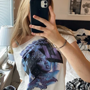 Avklippt t-shirt med tryck - En vit t-shirt som jag har klippt till själv med ett blå/rosa trycka av artistern Lizzo 