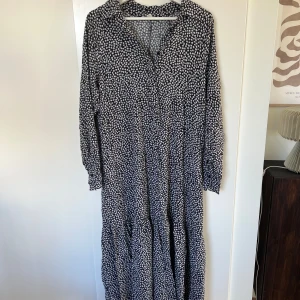 Klänning - Fin lång klänning med ett väldigt skönt material. Svart med vita blommor. Storlek S/36. Sparsamt använd💕