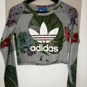 Blommig adidas magtröja - Jätte fint skick då jag aldrig hann använda den innan ja blev gravid. Supersöt tröja. Köparen står för frakt 