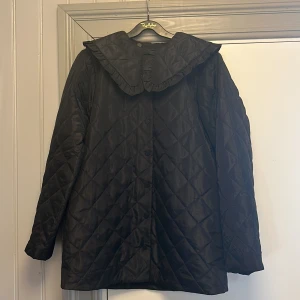 Quiltad jacka  - Svart vårjacka från HM. Klädda knappar, dekorativ krage som enkelt kan tas bort. Storlek S men rymlig i modellen. 