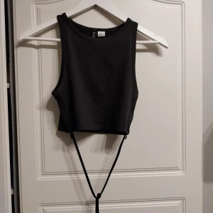 Svart topp - Svart topp med band att knyta runt magen. Toppen har använts två gånger så den är i bra skick. 
