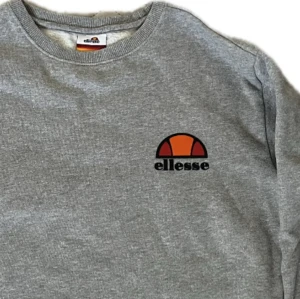 Grå Ellessetröja - Grå collegetröja från Ellesse med litet märke på bröstet. Storlek XS/ 12 år