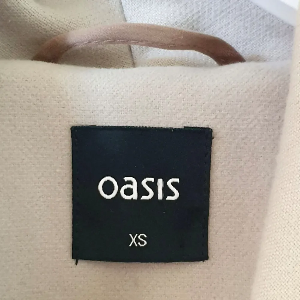 Färg: beige Strl: XS   Skitsnygg kortare kappa från Oasis. Knytband i midjan. Två dolda fickor på varsin sida. Slagkrage, som kan vikas in eller vikas ut. Använd men i gott begagnat skick! . Jackor.