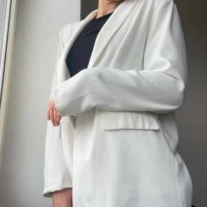 Vit kavaj med axelvaddar - Vit kavaj med lite axelvaddar. Säljer pga att jag aldrig använder den. Har vanligtvis storlek 36-38 men denna är i 40 för en lite mer oversized look. I gott skick!