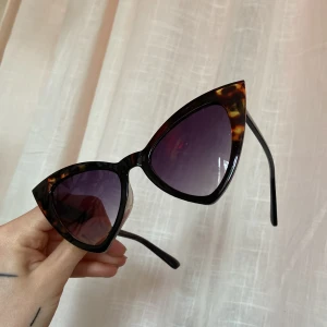 Kattformade solglasögon  - 60tals inspirerade solglasögon med melerad båge och aningen lila glas. Oanvända!