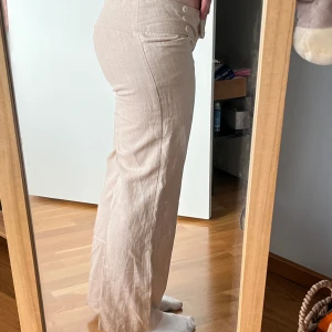 Beiga linnebyxor - Beiga linnebyxor i lite tjockare material. Det är en liten guldtråd i hela tyget, som inte syns så bra på bild, men den gör att byxan skimrar väldigt fint när solen lyser:) midja: 39 cm innerbenslängd: 72 cm ytterbenslängd: 92 cm