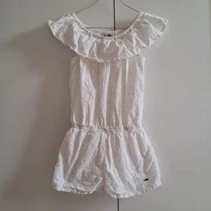 Somrig kort jumpsuit i spets  - Kort jumpsuit i spets, off shoulder (kan bäras som krage) från Kappahls kollektion "Hampton Republic" // Små skavanker i form av: missfärgning vid armen, liten fläck (syns knappt) samt några lösa trådar, se bild 3 // Skicka pm för mer info/samtal