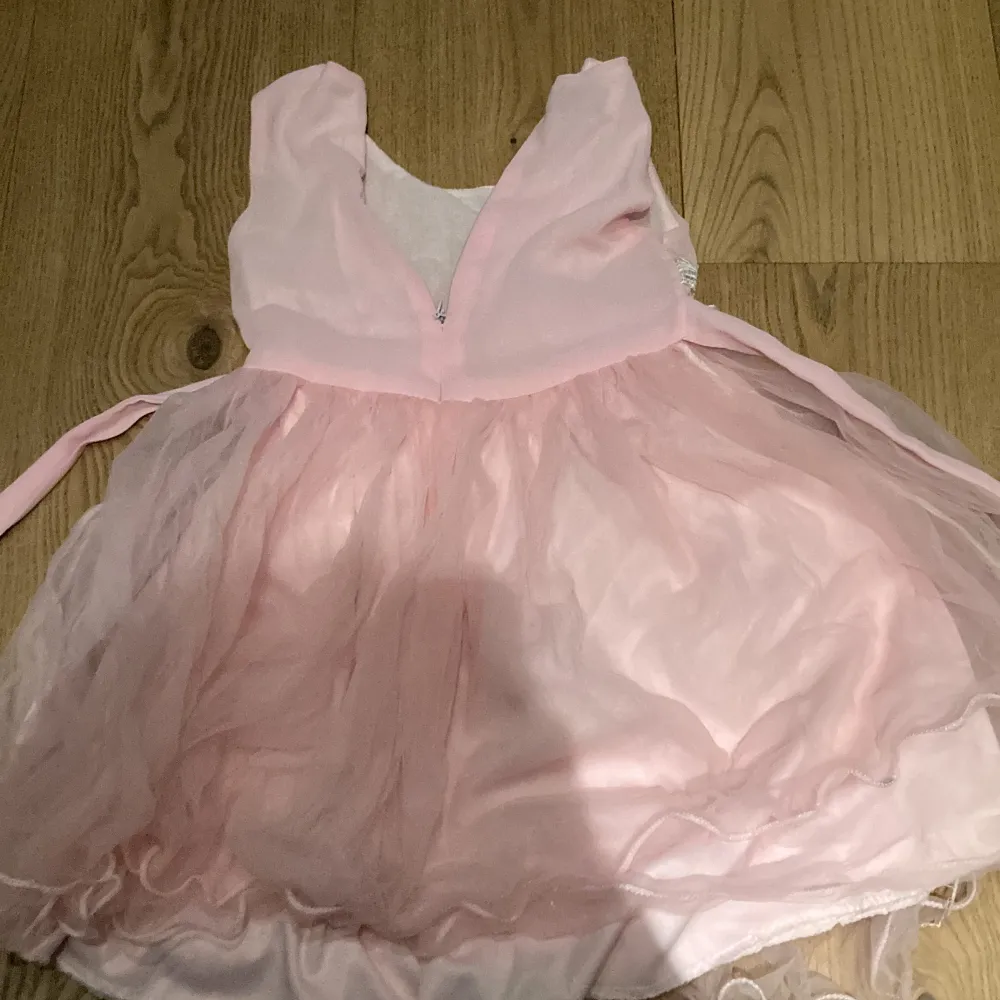 En rosa finklänning för barn med ros detaljer men även snören att knyta där bak. Fint skick.. Klänningar.