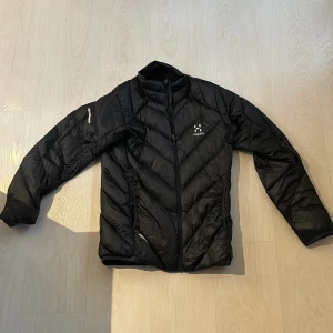 Haglöfs lättviktsdun - Säljer denna haglöfs jackan. Snygg och är i fint skick. Ända nackdelen är ett litet hål i ärmen som visas på tredje bilden, annars felfri.  Nypris 1500 kr.