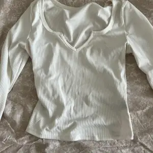 En enkel vit långärmad tröja med detalj vid brösten 