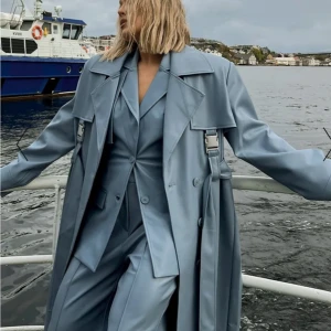 Blå trenchcoat PU - Trenchcoat i läderimitation från Angelica Blick x NA-KD. Helt oanvänd med prislapp kvar. Nypris 1000kr. 