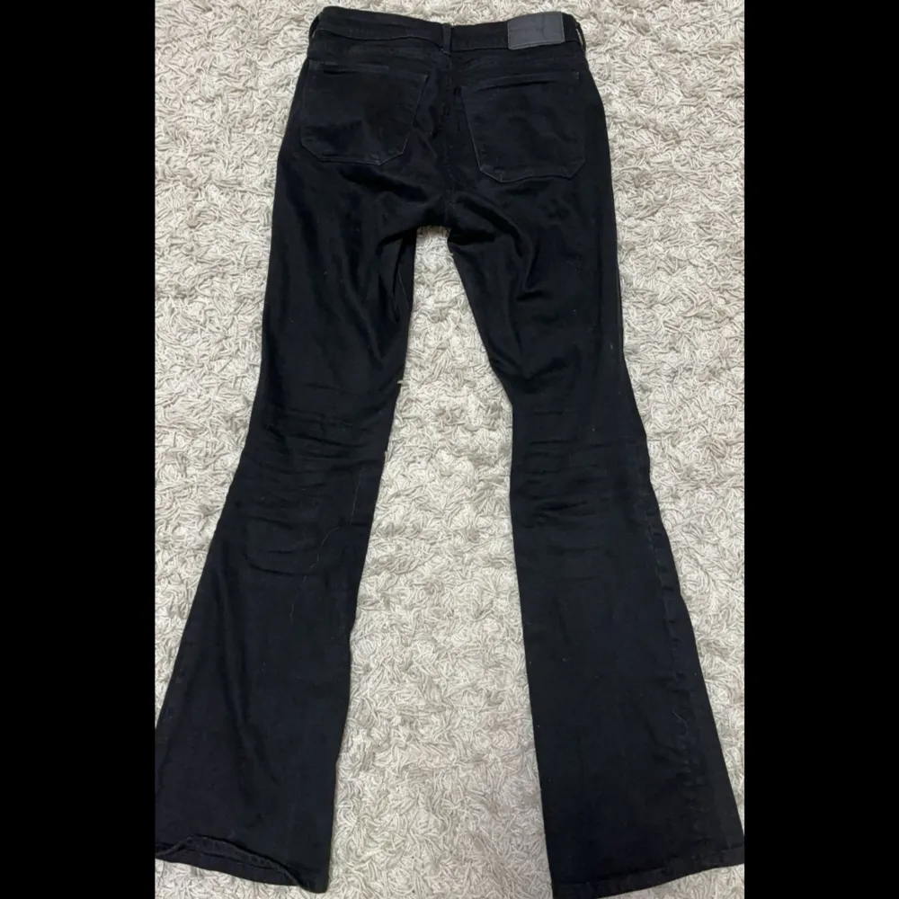 Svarta Low waist bootcut jeans med hål i knäna väldigt använda men bra skick. Jeans & Byxor.
