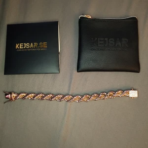 Cordell armband 18K - Köpt på kejsar.se för ca 1 år sedan. Använt 2 gånger (en av gångerna för att ta bilden till annonsen) jag tyckte den såg för "maffig" ut på mig så jag har haft den som prydnad på hyllan ist. Längd 21cm, bredd 10mm, guldpläterad med diamant lås.